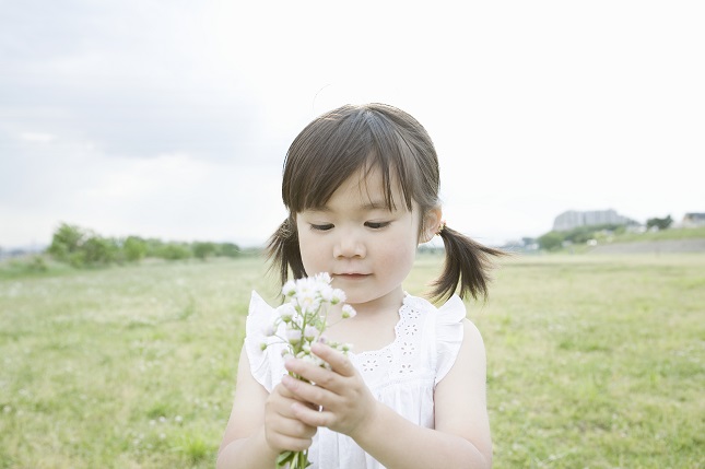 A girl standing in a field with flowers in hand