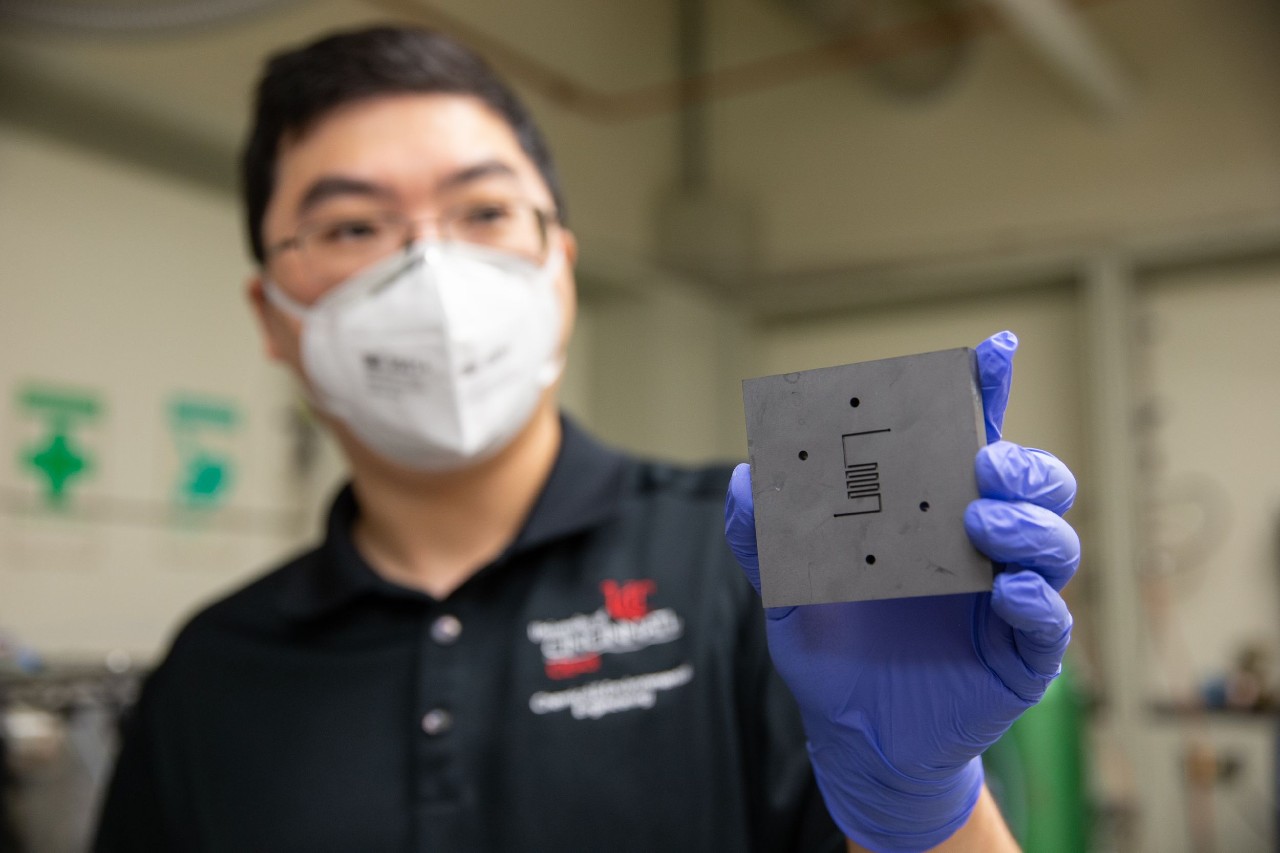 UC chemical engineer Jingjie Wu holds up the reactor where a catalyst converts carbon dioxide into methane. UC's research makes him optimistic that scientists will be able to remove carbon dioxide from the atmosphere