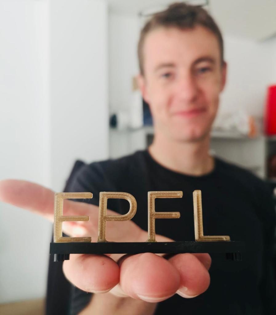 Lorenz Manker, the study's lead author, holding a 3D-printed EPFL logo made with the bioplastic. 