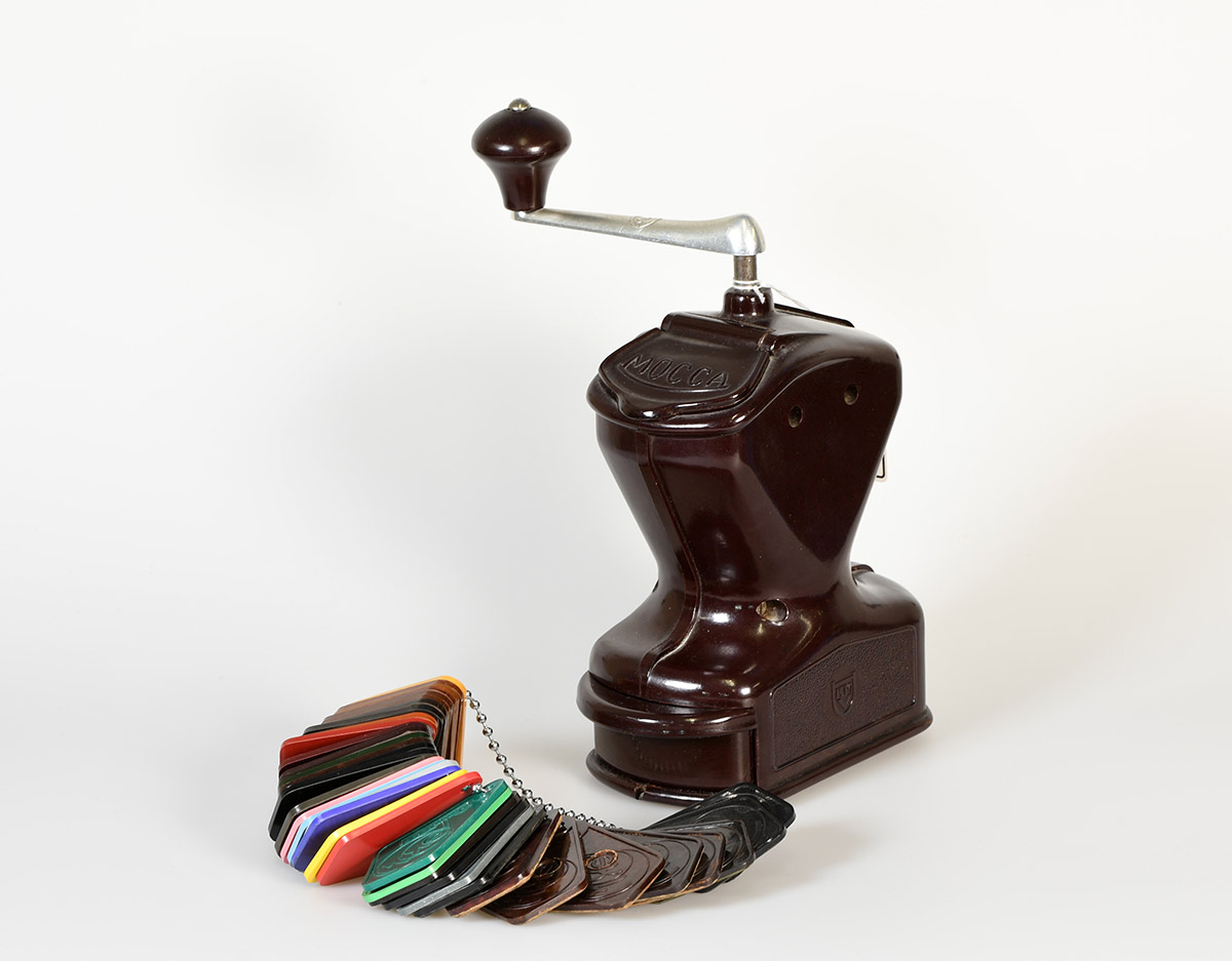 Kaffeemühle aus den 1920er Jahren, abgebildet mit einer Farbmusterkette aus dem gleichen Material, nämlich Phenoplast.
