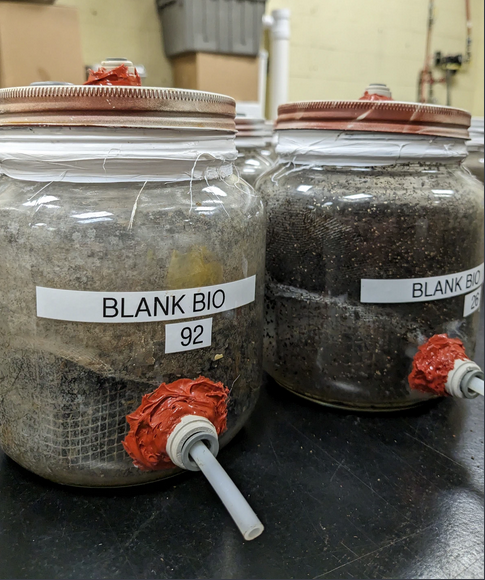 A close-up shows the bioreactors the Auras lab at Michigan State University has built to conduct biodegradation experiments. The bioreactors are essentially large glass jars with tubing to measure the gases produced during composting. 