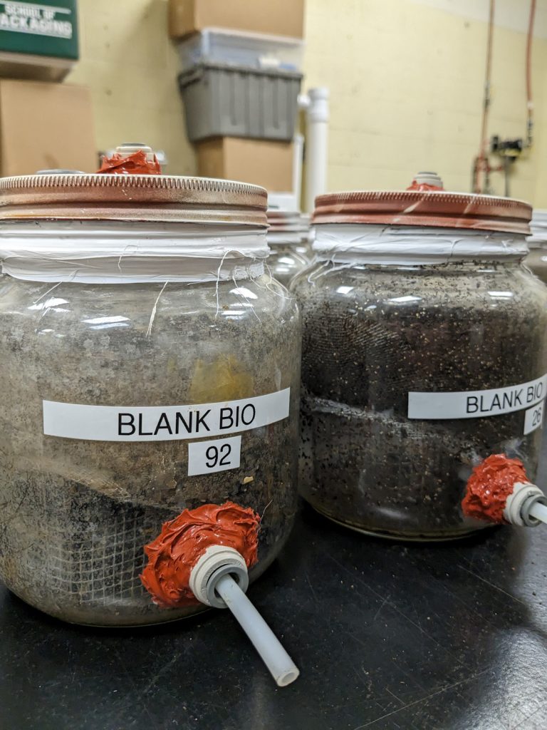 A close-up shows the bioreactors the Auras lab at Michigan State University has built to conduct biodegradation experiments. The bioreactors are essentially large glass jars with tubing to measure the gases produced during composting