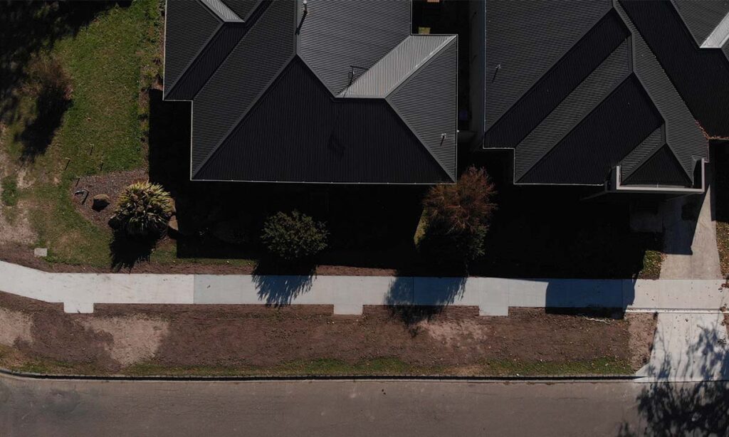 Aerial view of the finished footpath in Gisborne. The three panels attached to the footpath indicate different types of concrete used in the footpath, as part of the trial. The right panel indicates the section using coffee biochar in the concrete; the middle section uses wood chip biochar; the left section is the control, which uses standard concrete ingredients only. 