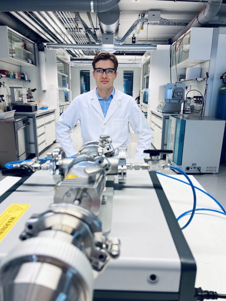 Cedric David Koolen, co-lead-author of the study, posing with the spark ablation device used to generate the clusters in the Laboratory of Materials for Renewable Energy.