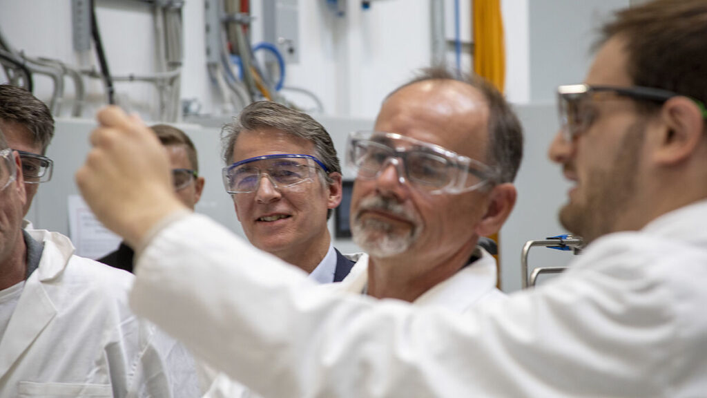 Dr. Wolfgang Blank, Wirtschaftsminister M-V verfolgt wie die FormaPort-Projektpartner, darunter Prof. Dr. Mathias Wilichowski (hinten) die Erläuterungen des AKROS-Geschäftsführers, Jonas Massa, in der Halle des im Leibniz-Institutes für Katalyse e. V.