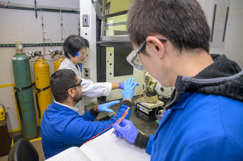 Dongxia Liu, professor of chemical and biomolecular engineering, and doctoral candidate Ali Kamali check the pressurized reactor used to convert plastic into fuel, while postdoctoral researcher Song Luo takes notes.