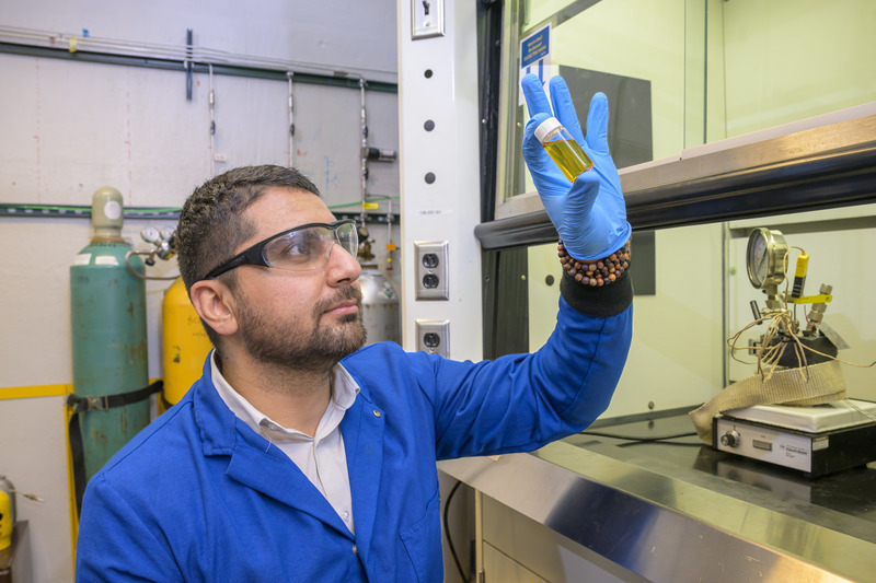 Ali Kamali, a doctoral candidate in chemical and biomolecular engineering, inspects a sample of liquid fuel created from plastics.