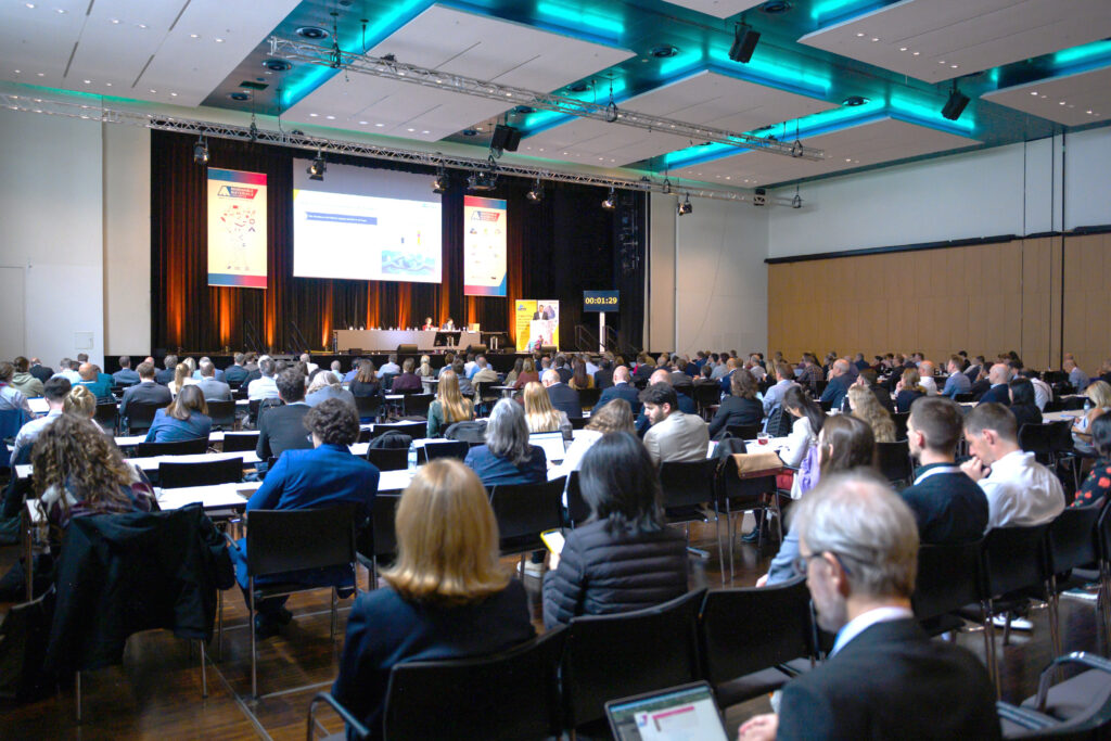 A full conference hall with attendees listening to presentations.