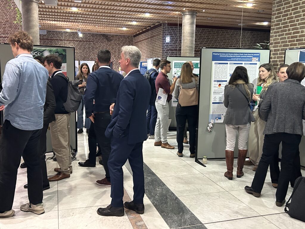 Experts gather closely around a detailed poster, discussing research findings in depth, which demonstrates the prime networking and visibility prospects for presenters.