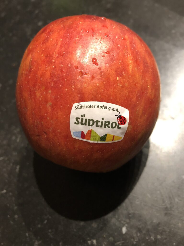 Ein roter Apfel mit Zertifizierung auf schwarzem Hintergrund – Symbol für biologisch abbaubare Kennzeichnung in der Landwirtschaft.