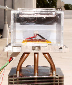 The harvester sitting atop a roof at MIT. The MOF is just below the glass plate on top, which lets sunlight in to heat the MOF and drive off the absorbed water. The yellow and red condenser sitting at the bottom is covered with water droplets. MIT photo by Hyunho Kim.