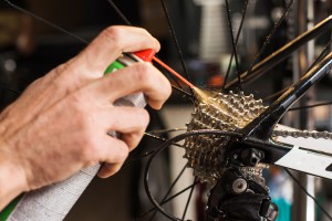 Male hands cleaning and oiling a bicycle chain and gear with oil spray