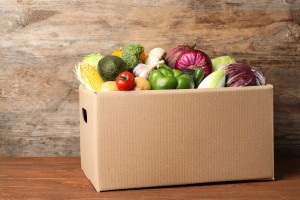 Fresh vegetables in cardboard box on wooden table