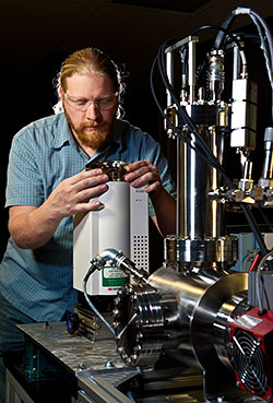 NREL researcher Robert Sykes loads a sample tray<br />onto the auto-sampler of the molecular beam mass<br />spectrometer, a key piece of NREL’s High Throughput<br />Analytical Process tool. Credit: Dennis Schroeder”></td>
</tr>
<tr>
<td style=