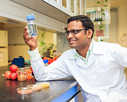 Mr Ramakrishna Mallampati, a PhD candidate at the<br />Department of Chemistry at NUS, demonstrating how<br />pollutants can be removed from water using apple peels.”></td>
</tr>
<tr>
<td style=